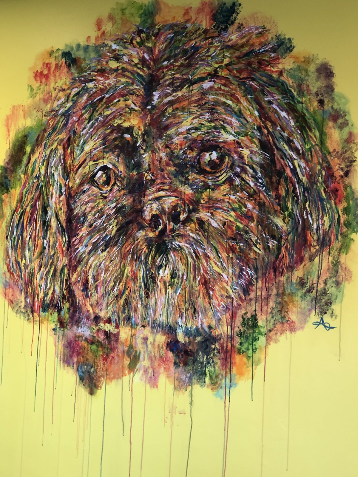 A large painting of a shaggy dog in reds, oranges and greens on the salon's yellow wall