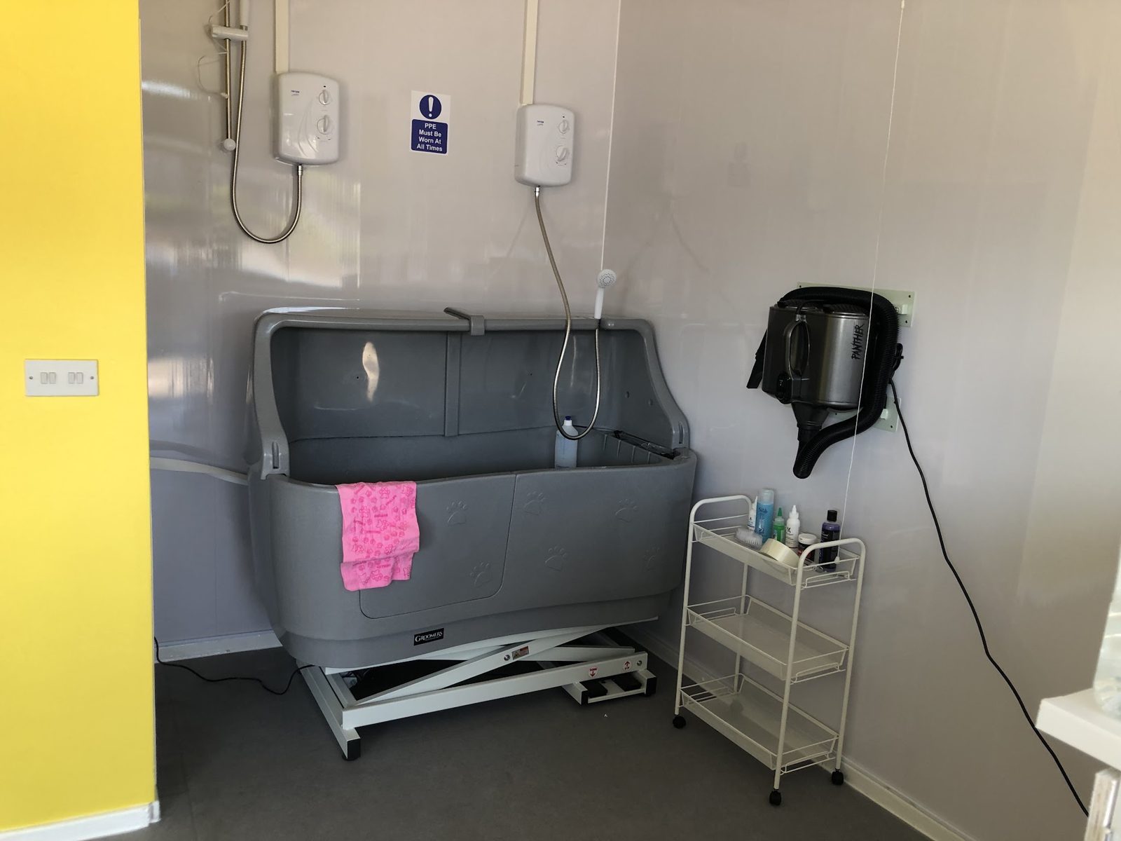 The bathing station at Bertie's House, a raised dog bath with two showers and a wall-mounted dryer
